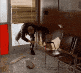 a man is standing in a waiting room with chairs and a broken glass door