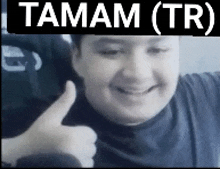 a man is smiling and giving a thumbs up in front of a banner that says tamam ( tr )