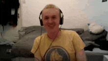 a man wearing headphones and a yellow shirt with a banana on it is smiling .