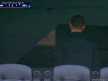 a man sits in a stadium watching a soccer game between the usa and an