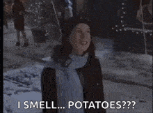 a woman wearing a scarf and hat is standing in the snow and says i smell potatoes