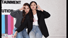 two women are posing for a picture in front of a sign that says tainment