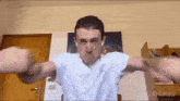 a man in a white shirt is making a funny face in front of a sign that says u / anthzu