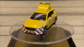 a yellow toy car is sitting on top of a glass display .