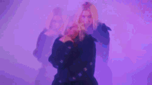 a woman wearing headphones is dancing in front of a purple background .