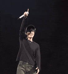 a man wearing a hat and a black shirt is holding a microphone in his hand