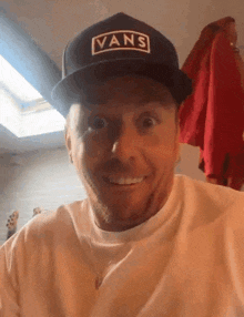 a man wearing a vans hat is smiling and looking at the camera