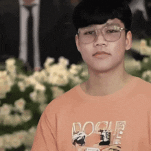 a young man wearing glasses and an orange vogue t-shirt