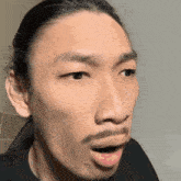 a man with long hair and a beard is making a surprised face