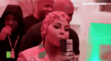 a woman is singing into a microphone in front of a crowd of people .
