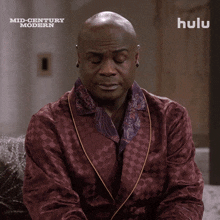 a man in a burgundy robe is sitting in front of a sign that says hulu