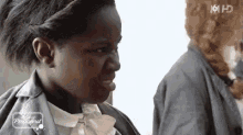 a woman is making a funny face while standing next to another woman in a black jacket .