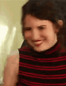 a woman in a striped shirt is smiling and making a funny face .