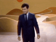 a man in a suit and tie is walking down a runway .