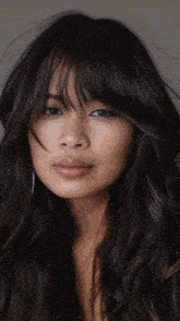 a woman with long dark hair and bangs looks at the camera