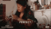 a woman is sitting at a table eating food and the word perfect is on the bottom of the image .