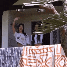 two girls are standing on a balcony with korean writing on the bottom