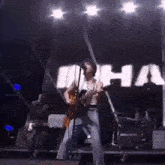 a man is playing a guitar and singing into a microphone while standing on a stage .