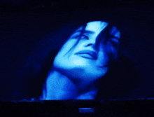 a close up of a woman 's face with blue light behind her