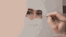a woman is painting a picture of her face with a brush .