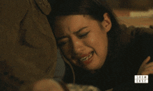 a woman is crying while a man holds her head in a show case photo