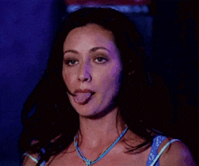a close up of a woman 's face with her eyes closed and her mouth open . she is wearing a blue necklace .