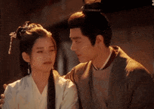a man and a woman are looking at each other . the woman is wearing a traditional costume .