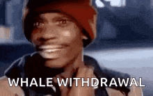 a man wearing a red hat and a black jacket is smiling and says `` whale withdrawal '' .