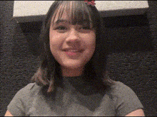 a young girl is smiling for the camera while wearing a gray shirt .