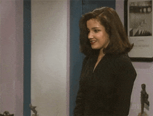 a woman in a black dress stands in front of a framed picture of a man