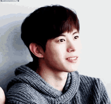 a close up of a young man wearing a sweater