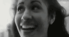 a black and white photo of a woman smiling with her mouth open .
