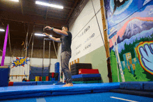 a man stands on a trampoline in front of a wall that says " turn of crisis "