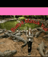 a woman stands in front of a pond surrounded by crocodiles with buaya masuk yuk written in red