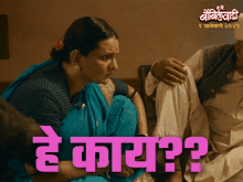 a woman in a blue saree sits next to a man in a white shirt and a sign that says " he kaay "