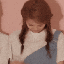 a girl with braids is wearing overalls and a white shirt .
