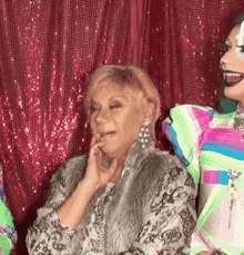 a woman in a fur coat is talking to another woman