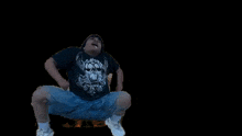 a man wearing a black shirt and blue shorts is jumping in the air .
