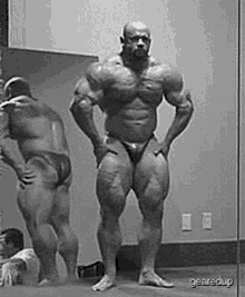 a muscular man is standing in front of a mirror in a gym .