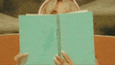 a woman covering her face with a book
