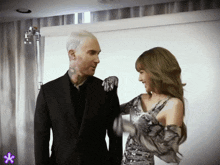 a man in a suit and a woman in a dress are talking to each other