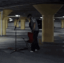a man stands in front of a microphone in a dark parking garage
