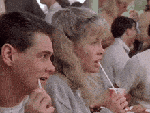 a man and a woman are drinking through straws in a crowded room