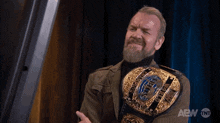 a man with a beard is wearing a aew belt