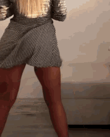 a woman in a plaid dress is dancing in front of a couch .