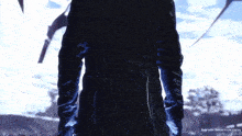 a man in a black coat and blue gloves is standing in the dark