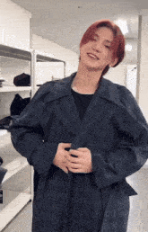 a man with red hair is standing in a room wearing a black coat