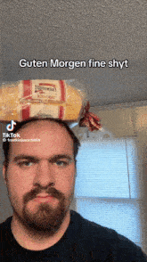 a man with a beard has a loaf of bread on top of his head
