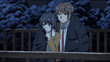 a boy and a girl are standing next to each other on a balcony at night