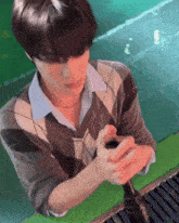 a man in a plaid sweater is holding a microphone in his hands